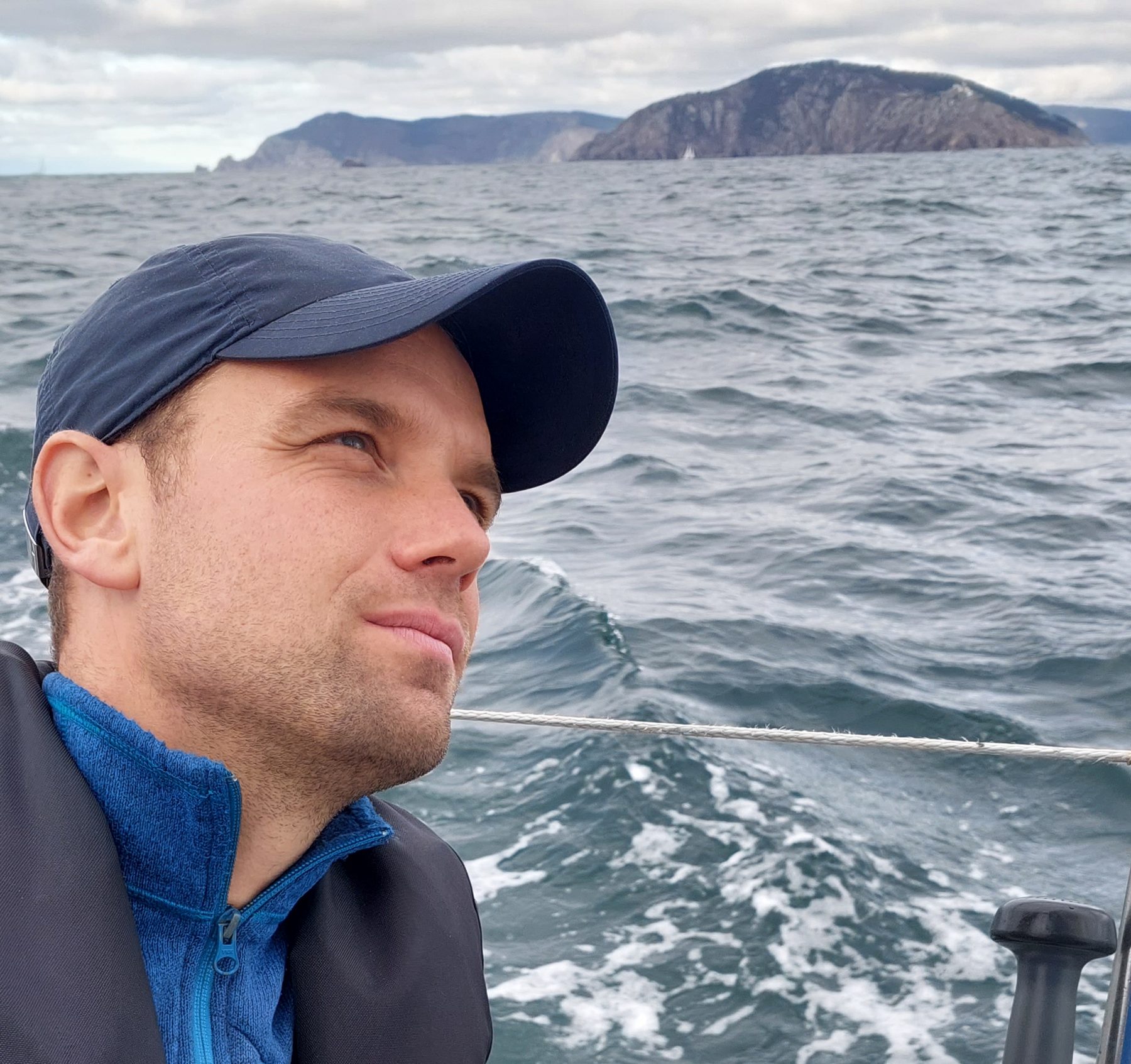 Lars Bosma aan het roer, kijkend over een onrustige zee