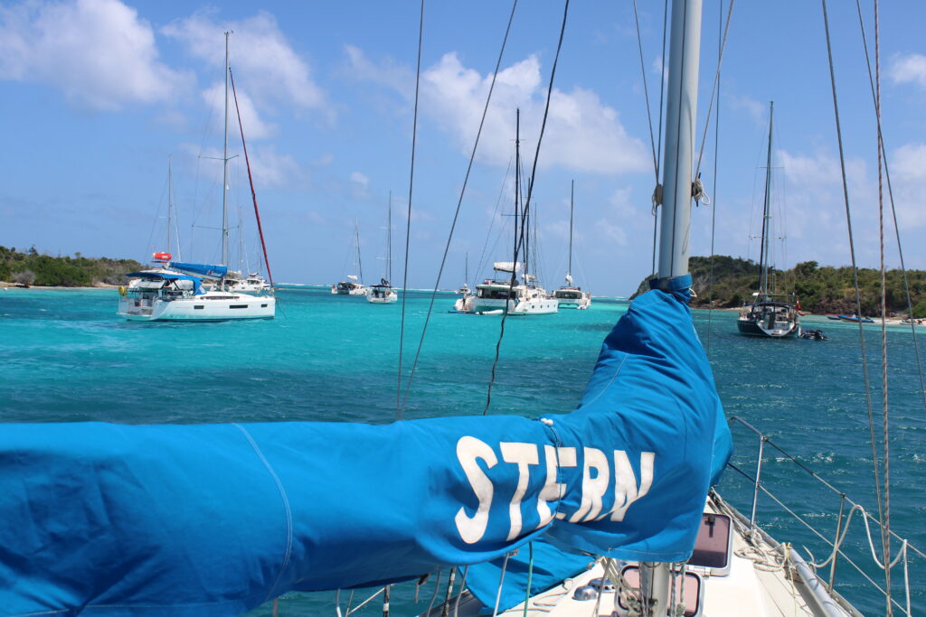 De Stern voor anker in turquoise water tussen andere zeilboten, met de naam Stern op de zeilhoes